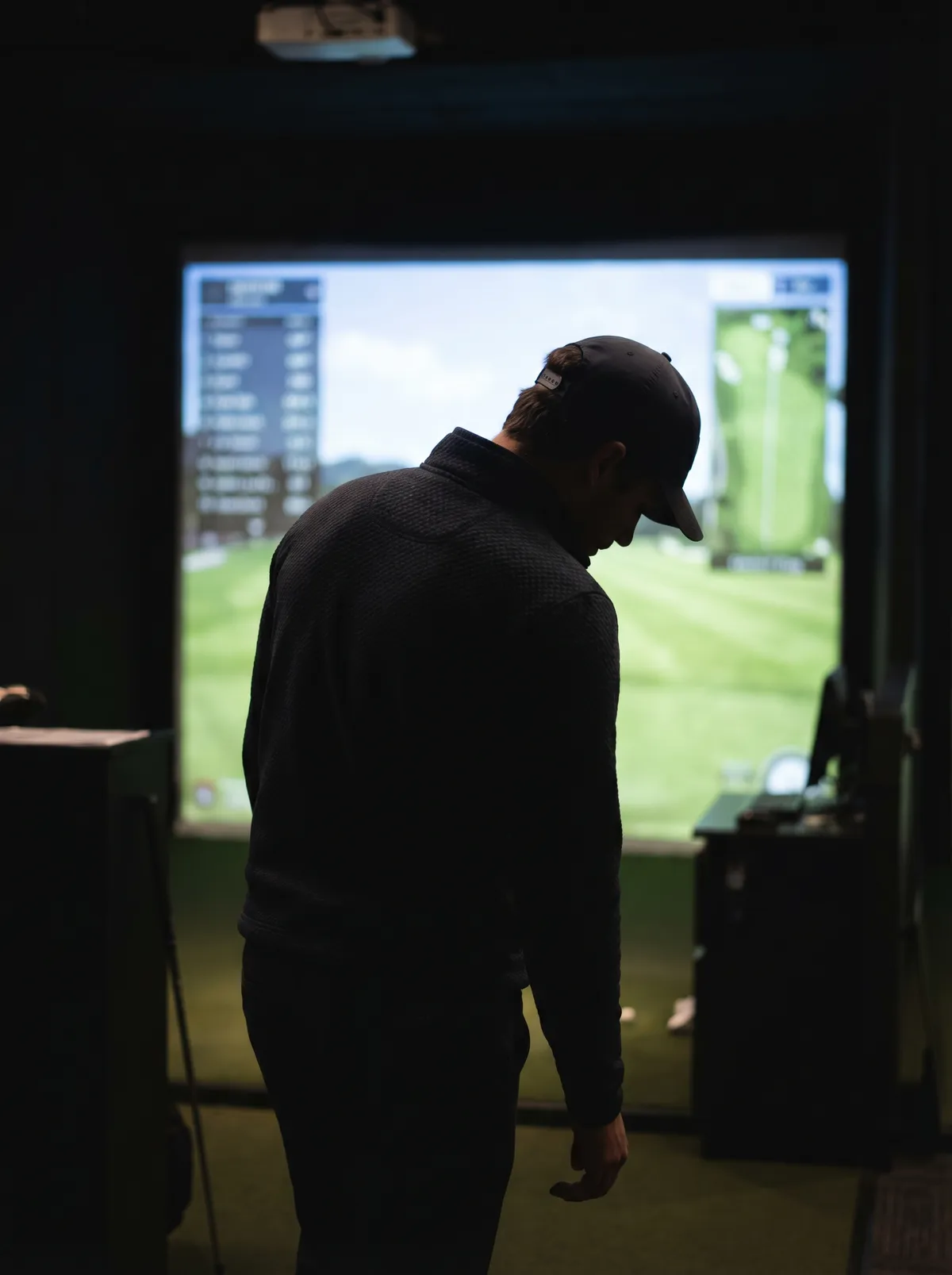 Golfer practicing at an indoor golf simulator during a booked session