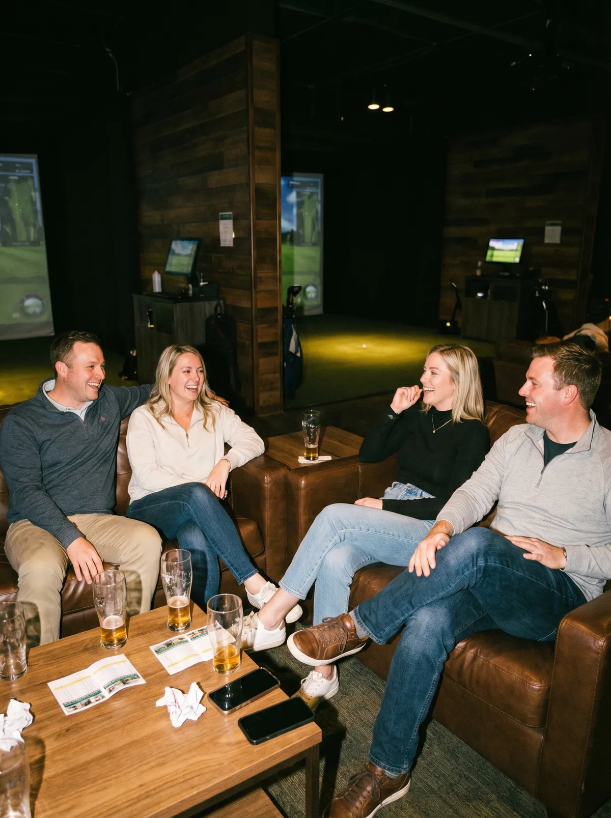 Group of friends enjoying drinks and socializing at an indoor golf simulator venue